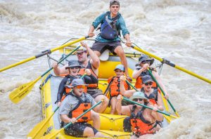 a group of men riding on the back of a boat in the water
